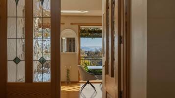 A room with a view through a window, a chair, and a door leading to another space.
