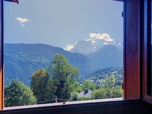 Uitzicht door een raam op een bergachtig landschap met heldere lucht.