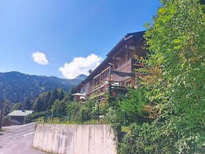 A wooden building with balconies, surrounded by greenery and mountains. - Les Grandes Aiguilles by Interhome (Saint Gervais)