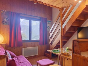 A wooden cabin interior with a dining table, a couch, and a staircase. - Les Grandes Aiguilles by Interhome (Saint Gervais)