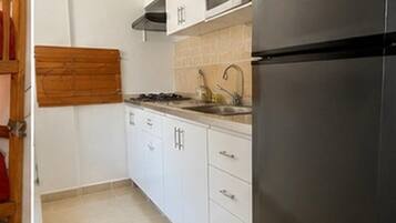A kitchen with white cabinets, a stainless steel refrigerator, a microwave, and a gas stove.