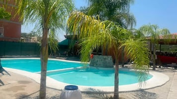 A swimming pool with palm trees and a stone structure in the background.