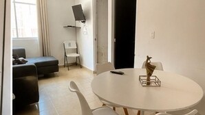 Huoneessa on pyöreä valkoinen pöytä, valkoiset tuolit, musta sohva ja valkoinen tuoli.
