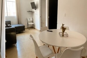 A room with a round white table, white chairs, a black sofa, and a white chair. - WHITE HOUSE HUATULCO (Bahía de Santa Cruz Huatulco)