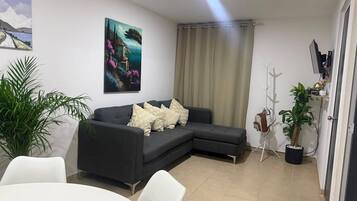 A modern living room with a sectional sofa, a dining table, and a potted plant.