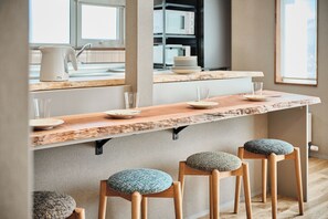 A kitchen with a wooden countertop, bar stools, and a window.