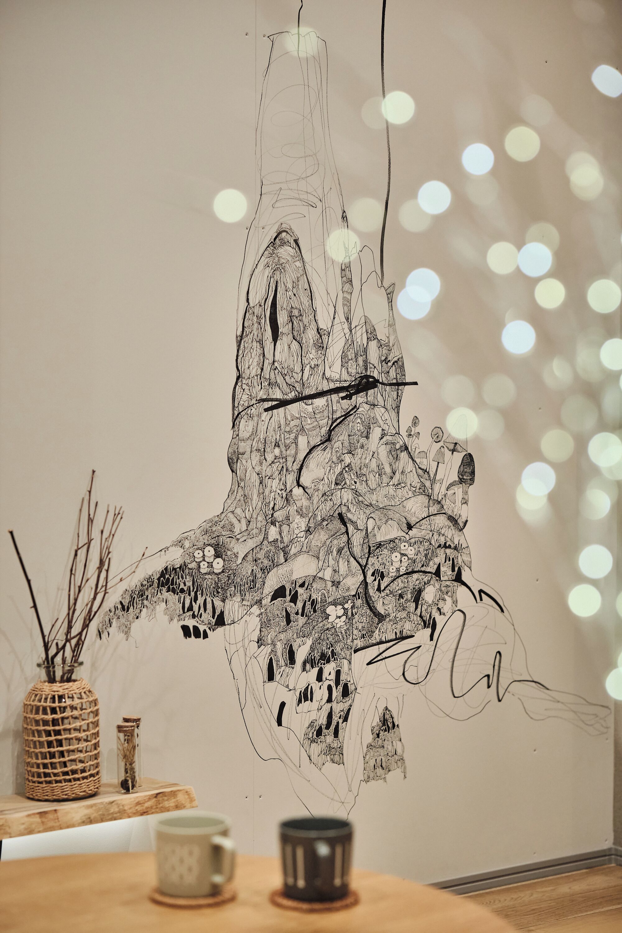 A wall with a large black and white drawing of a tree with branches and leaves.