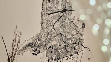A wall with a large black and white drawing of a tree with branches and leaves.