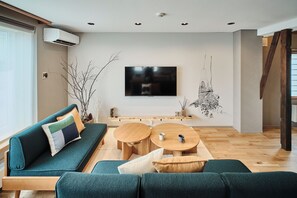 A modern living room with a sofa, coffee table, and a flat-screen TV mounted on the wall.