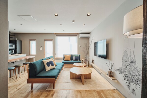 A modern living room with a sofa, coffee table, and a flat-screen TV mounted on the wall.