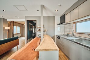 Una cocina moderna con una isla central, electrodomésticos de acero inoxidable y vistas al exterior.
