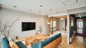 A modern interior with a seating area, a flat-screen TV, and a wooden floor.