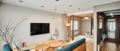 A modern interior with a seating area, a flat-screen TV, and a wooden floor.