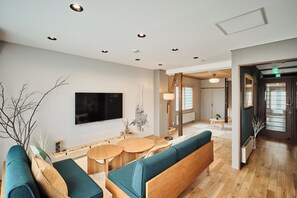 Un interior moderno con una zona de estar, un televisor de pantalla plana y piso de madera.