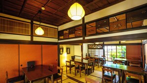 A traditional Japanese restaurant with tatami flooring, wooden furniture, and a view of greenery outside.