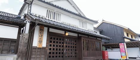 Un edificio japonés tradicional con un portón de madera, techo de tejas y un letrero.
