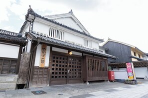 Um edifício japonês tradicional com um portão de entrada de madeira, telhado telhado e uma placa.