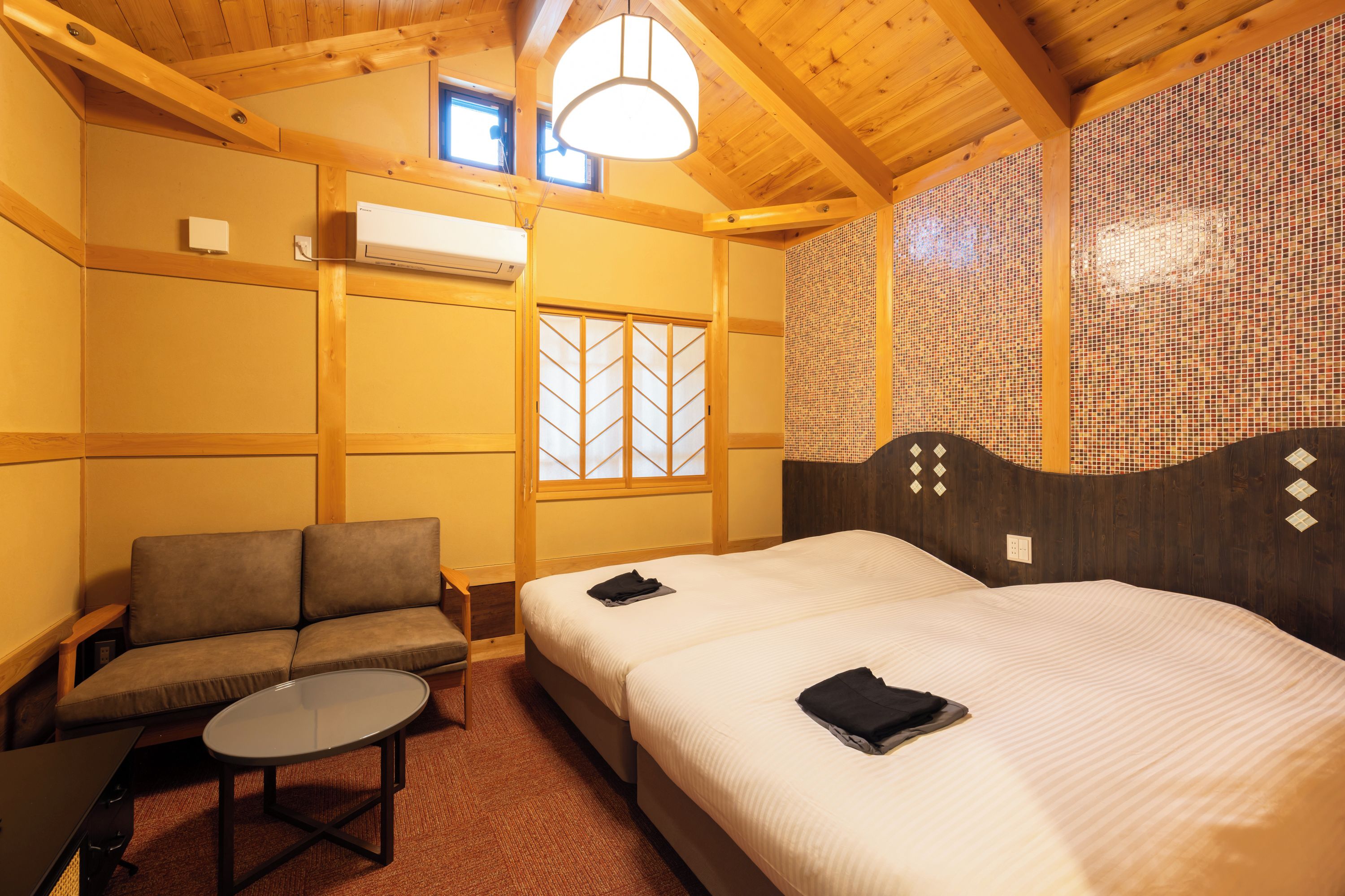 A hotel room with a bed, a sofa, a small table, and a window with a view.