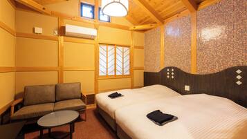 A hotel room with a bed, a sofa, a small table, and a window with a view.
