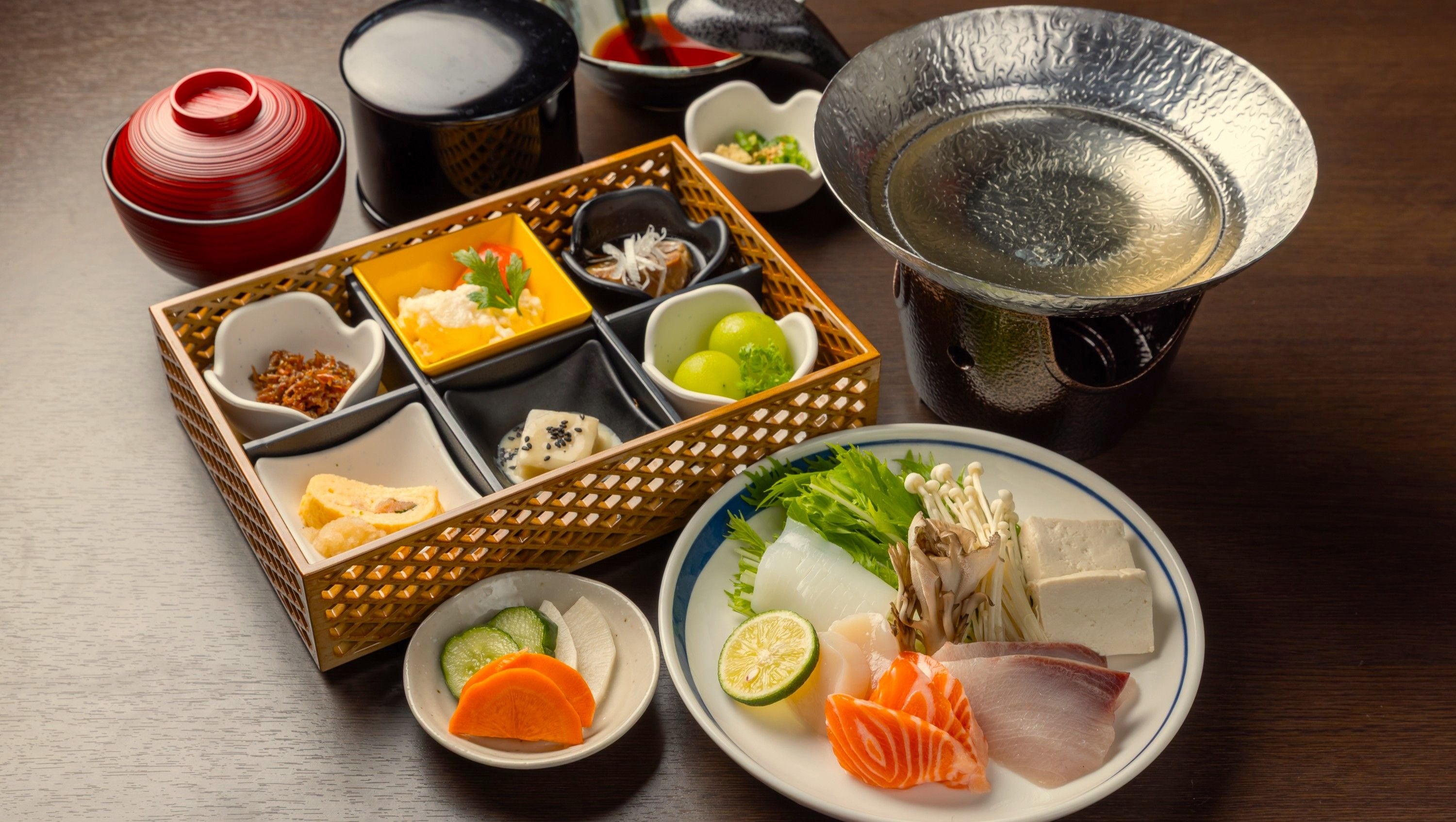 Una comida tradicional japonesa con diversos platos y una olla caliente.