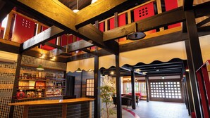 A restaurant interior with a wooden ceiling, tiled walls, and a counter with a plant.