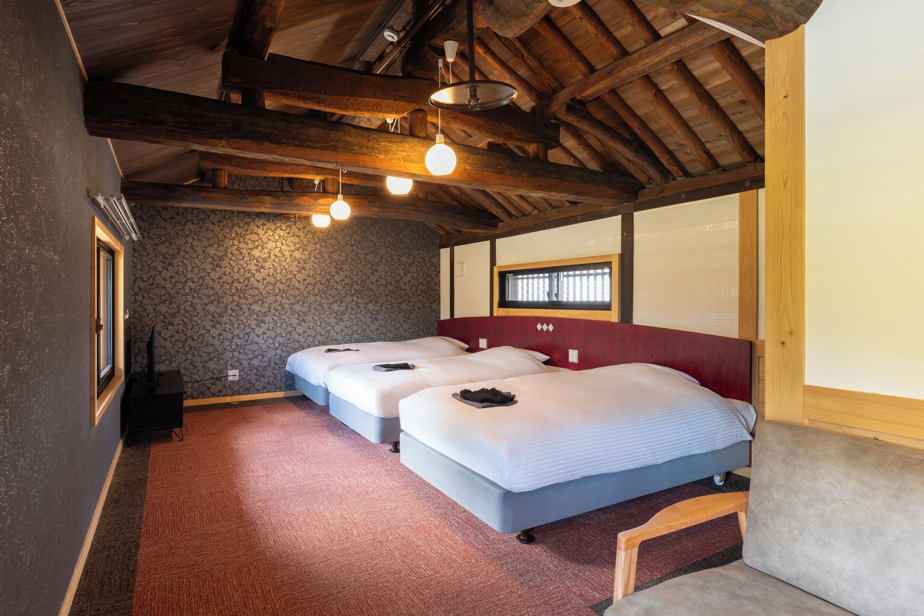 Una habitación con dos camas, techo de madera y pared con estampado.