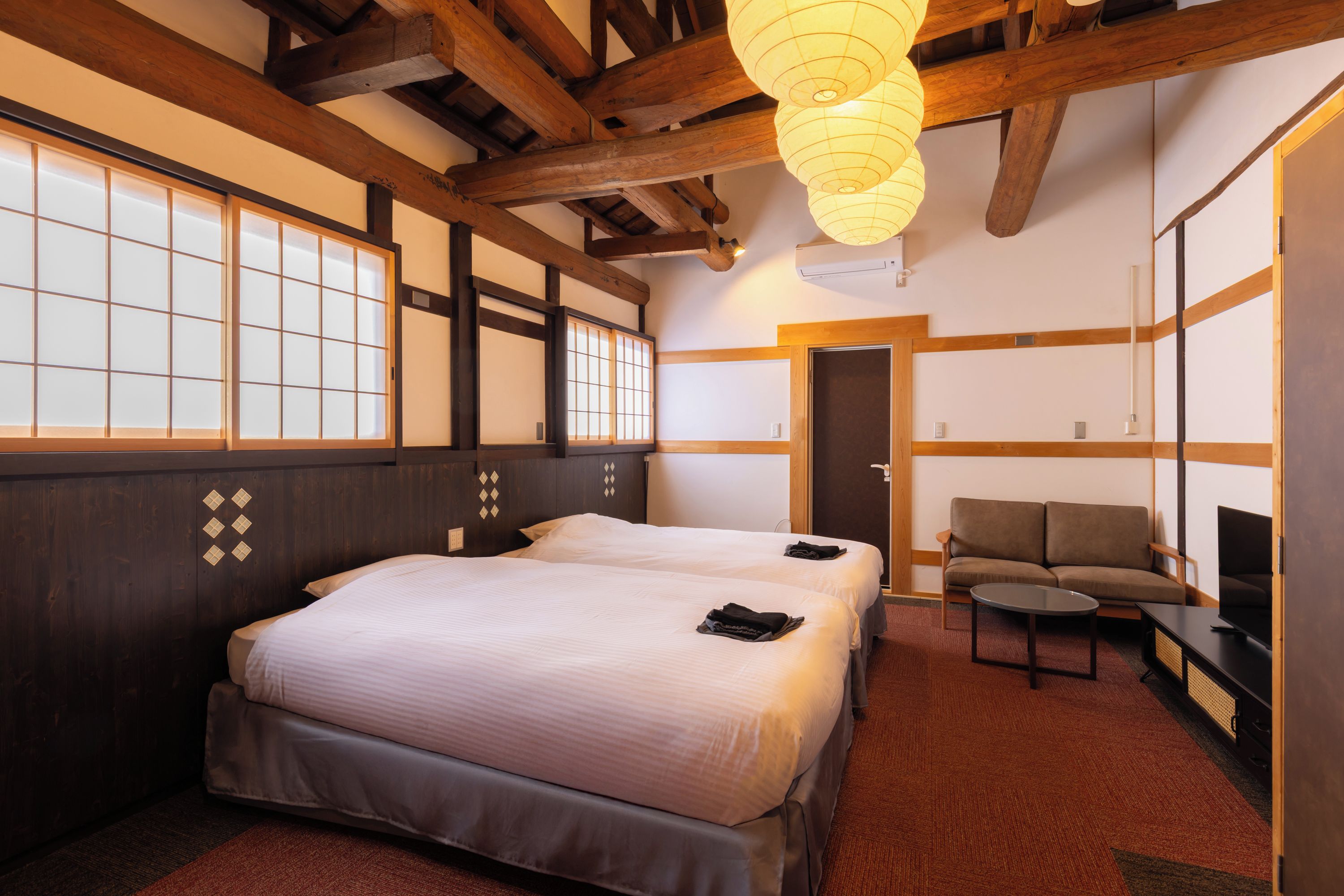 A hotel room with a large bed, a sofa, and a TV.
