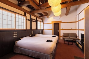A hotel room with a large bed, a sofa, and a TV.