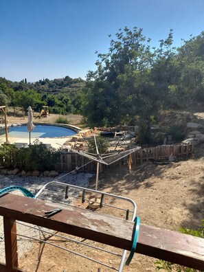 A pool area with a hammock, a wooden deck, and a view of a hilly landscape. - Tranquil Chalet Retreat With Shared Pool in Estói, Portugal (Faro)