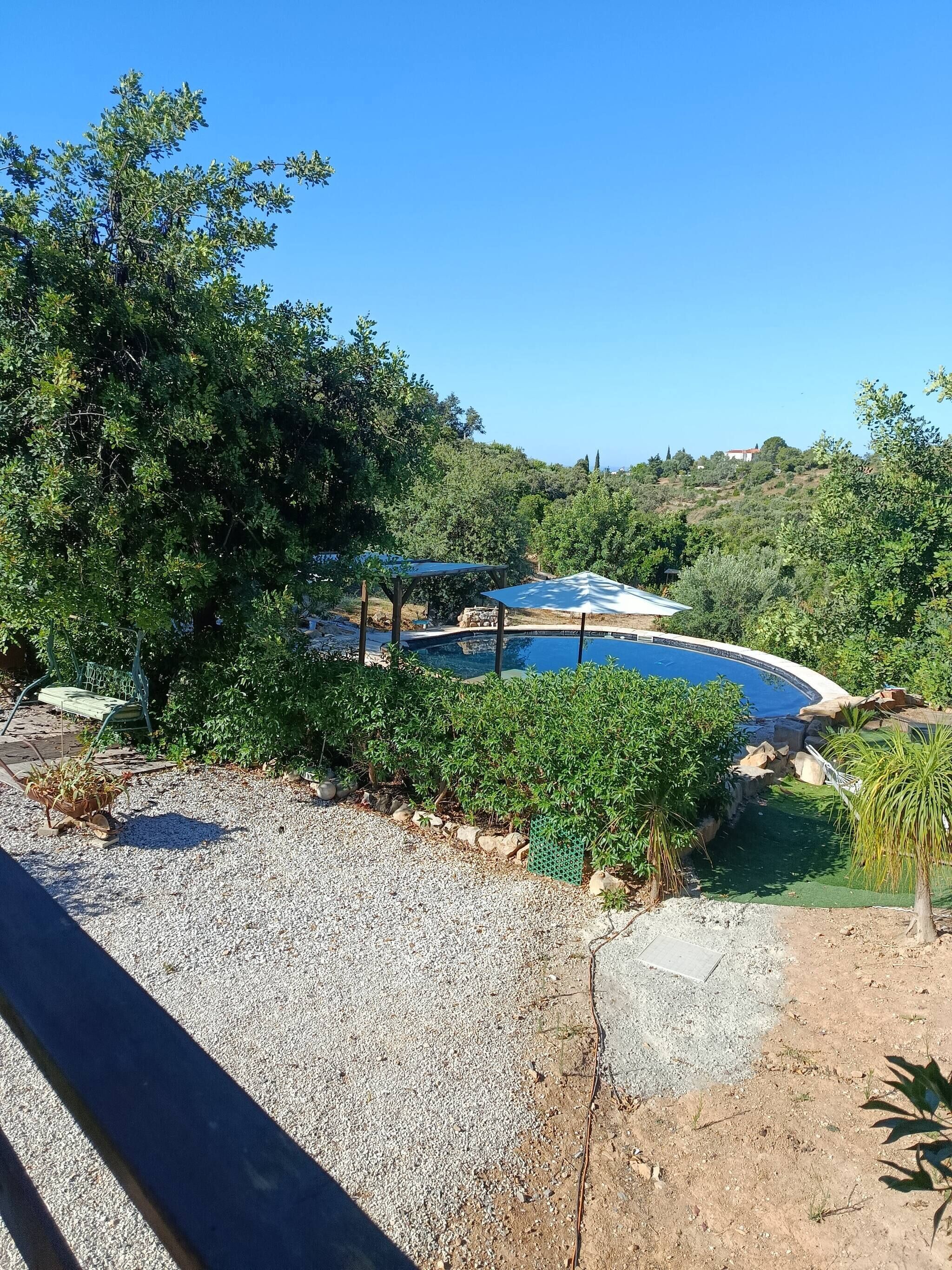 A pool area with a clear view of the surrounding landscape, including trees and hills.