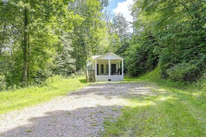 Een klein, gelijkvloers vakantiehuisje met een veranda, omringd door dicht bos.
