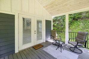 Eine überdachte Veranda mit zwei Stühlen und einem Tisch, eine Tür mit Fenster und einer Fußmatte.