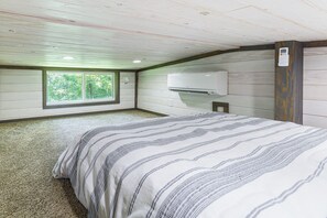 A bedroom with a bed, a window, an air conditioning unit, and a carpeted floor. - Relax in Style - Serene Getaway Near Mountain City (Mountain City)