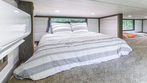 A bedroom with a large bed, a window, and a view of greenery outside.