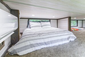 A bedroom with a large bed, a window, and a view of greenery outside.