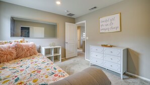 Un dormitorio con cama, cómoda y una frase motivadora en la pared.