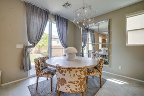 A dining area with a round table, two chairs with a spotted pattern, a white vase with flowers, and a large mirror on the wall. - Stylish Family Home w/ Playground in Las Vegas (Las Vegas)