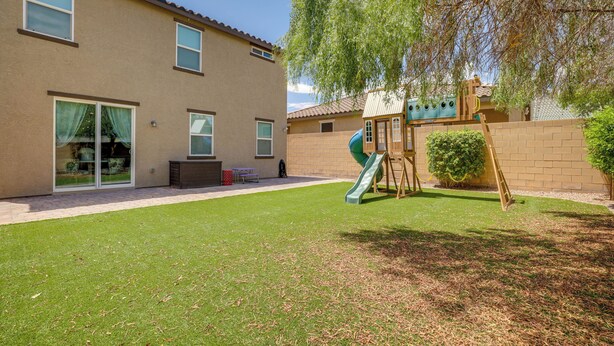 Edificio residencial con patio trasero que incluye un parque infantil, un patio y un césped.