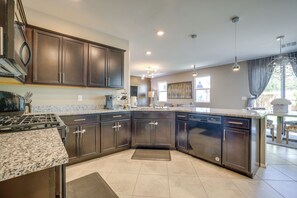 Une cuisine moderne avec des meubles de couleur sombre, des plans de travail en granit, une cuisinière encastrée et un lave-vaisselle.