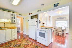 A kitchen with white cabinets, a refrigerator, an oven, and a dining area with a table and chairs. - Walk to Dtwn Clayton & River! 2-Unit Getaway (Clayton)