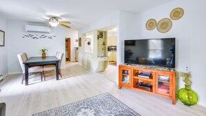 Ein modernes Wohnzimmer mit Essbereich, Fernseher und einer grünen Vase.