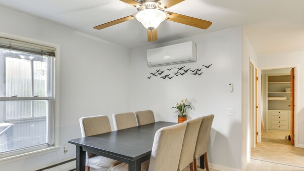 Ein Essbereich mit Tisch, Stühlen, Deckenventilator, Klimaanlage und einem Fenster mit Jalousien.