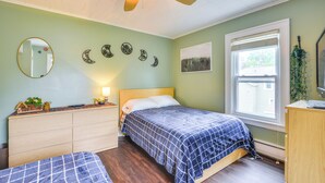 Ein Schlafzimmer mit einem Bett, einem Schminktisch, einem Spiegel, einem Deckenventilator und einem Fenster mit Jalousien.
