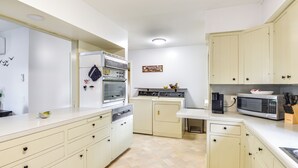 Eine kompakte Küche mit Geschirrspüler, Backofen, Mikrowelle und Kaffeemaschine.