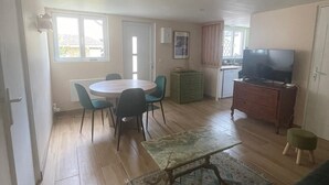 Een ruime woonkamer met een eettafel, stoelen, een bank, een televisie en een keuken op de achtergrond.