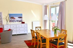 Ein Essbereich mit Holztisch und -stühlen, einem weißen Schrank und einem Gemälde an der Wand.