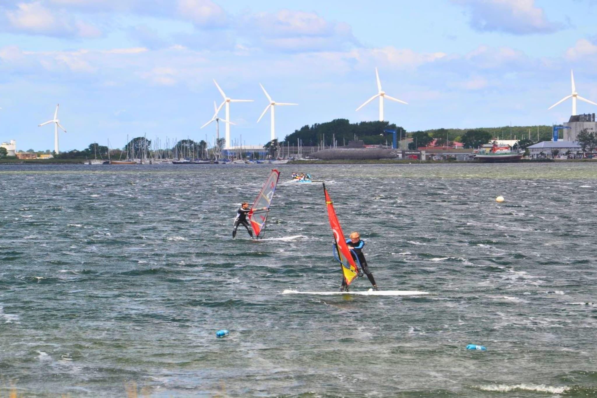 Un plan d’eau avec des éoliennes en arrière-plan.