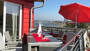 Un'area pranzo all'aperto con tavolo, sedie e un ombrellone rosso.