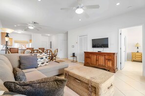 A modern living room with a sofa, a television, and a wooden cabinet. - Kaibo Yacht Club  2 Bdr Beachfront Condo Hot Tub and Pool (Rum Point)