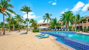 Um resort com piscina, espreguiçadeiras e palmeiras.